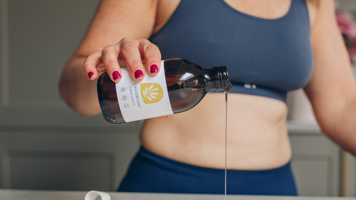 woman pouring Castorvida castor oil onto a castor oil compress